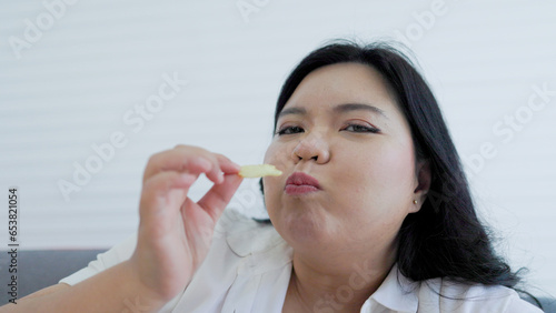 chubby asian woman happy eating potato snacks