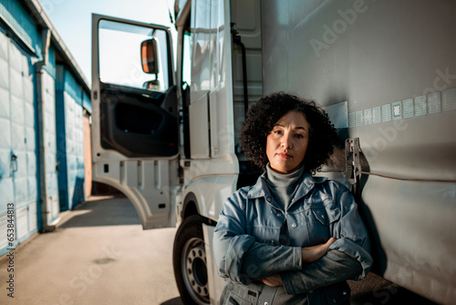 Portrait of a confident young female truck driver in front of her vehicle photo