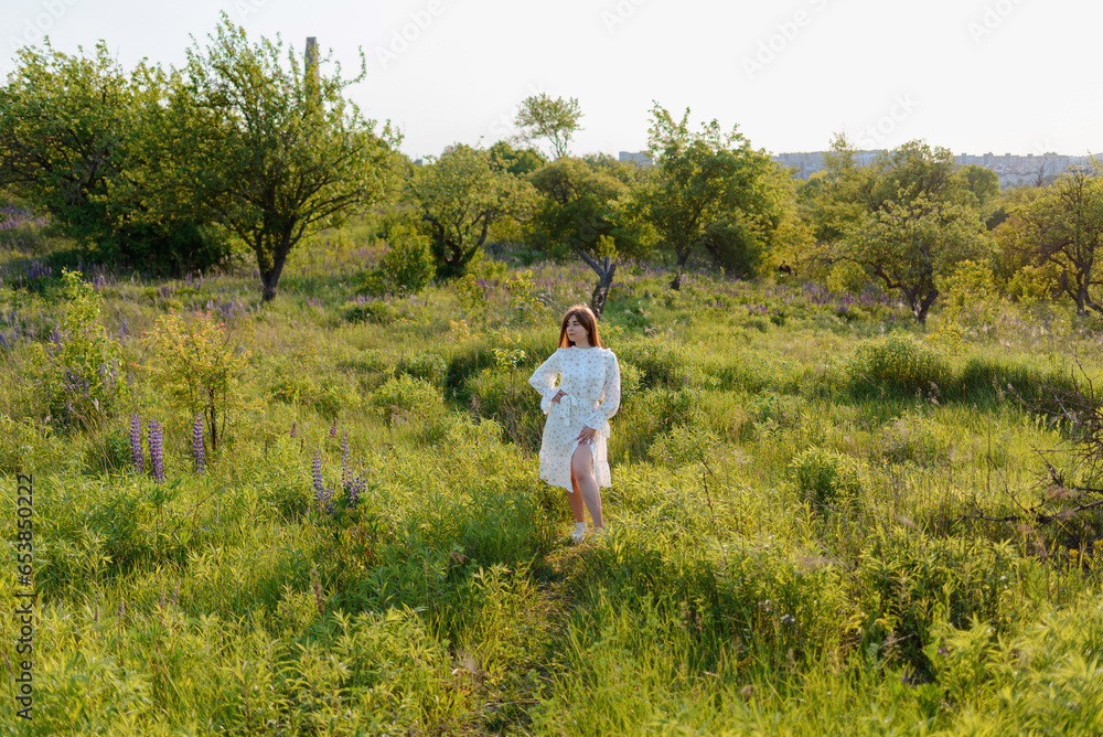A woman walking around lupine flowers and a tree in a park A woman walking around lupine flowers and a tree in a park