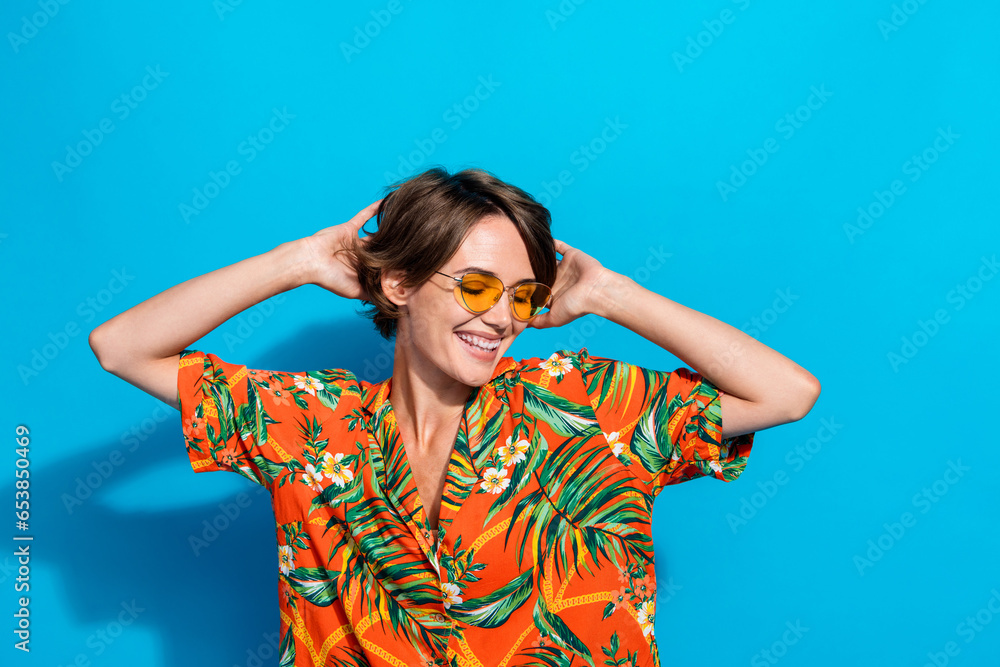 Portrait of positive lovely girl toothy smile hands touch head dancing enjoy free time isolated on blue color background Portrait of positive lovely girl toothy smile hands touch head dancing enjoy free time isolated on blue color background