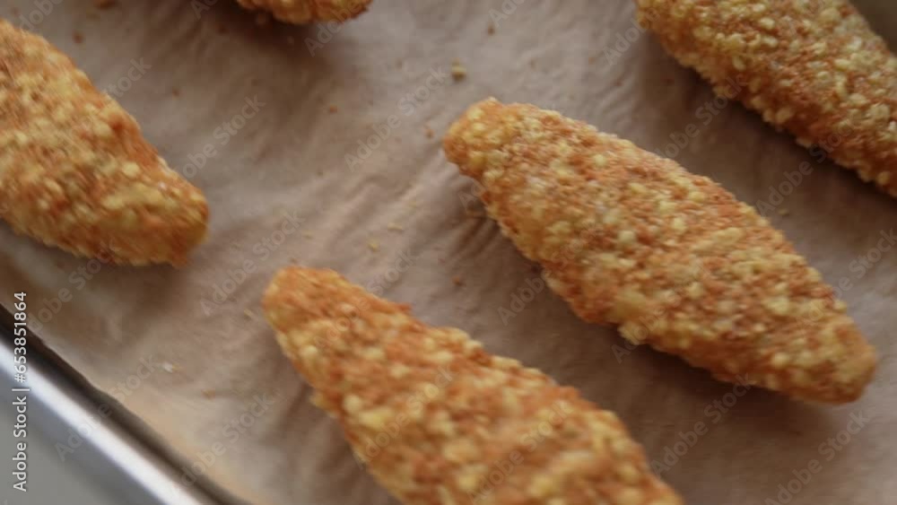 Raw frozen breaded chicken pieces on a baking sheet. Raw frozen breaded chicken pieces on a baking sheet.