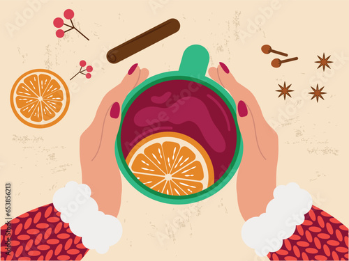 Female hands in a woolen sweater hold a cup of mulled wine, tea with a slice of orange, around there are ingredients for mulled wine, cinnamon, cloves, cardamom. Top view.