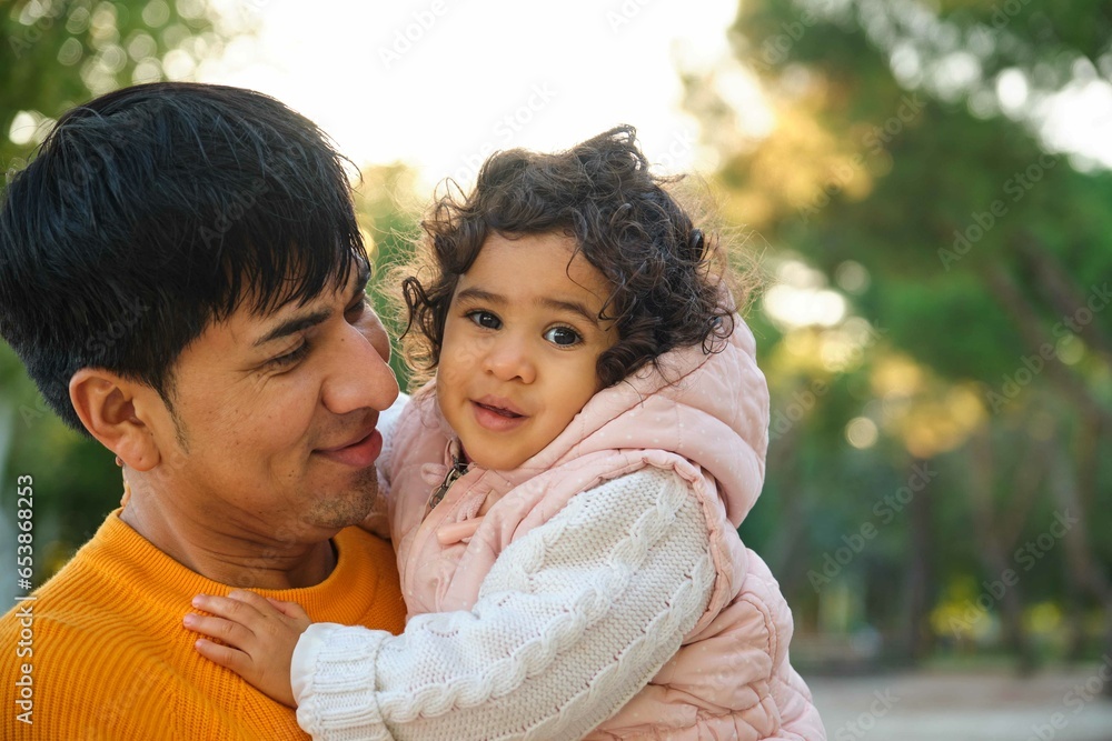 Portrait of happy Ecuadorian father holding her one year old daughter in a park. Portrait of happy Ecuadorian father holding her one year old daughter in a park.