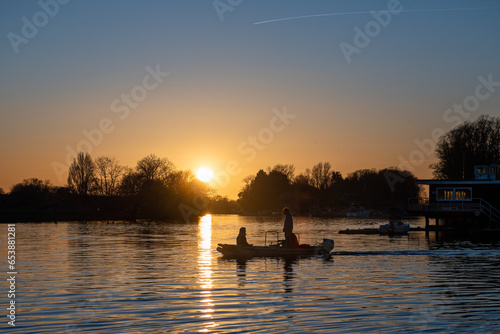 People crossing the river Thames in a small motor boat at sunset on a wintery evening