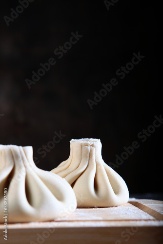 Dumplings are made by hand. Cooking dumplings or cooking khinkali. Traditional Georgian dish. Vertical photo. Black background. Copy space.