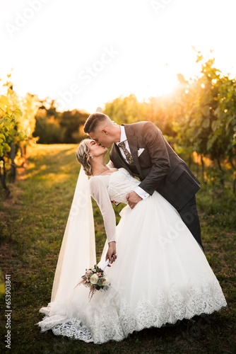 beautiful bride in white dress and groom kissing in the middle of vineyard and grapes, groom holding bride,sunny day, love is in the air, wedding photography