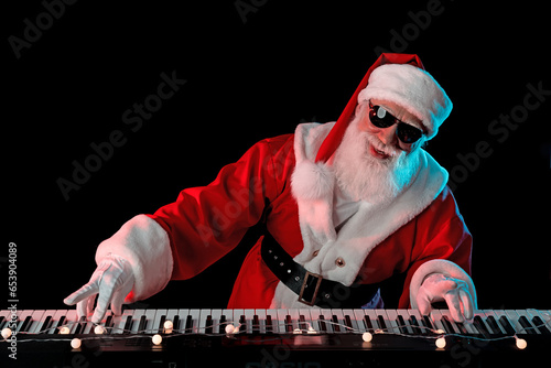 Santa Claus playing the electric piano in a nightclub at a Christmas and New Year party or Corporate events. Senior piano player as Santa at a concert, festival, or celebration