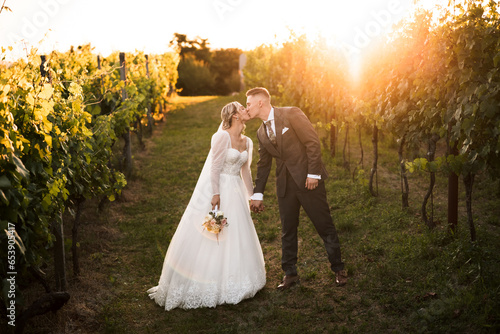 beautiful bride in white dress and groom kissing in the middle of vineyard and grapes, groom holding bride,sunny day, love is in the air, wedding photography photo
