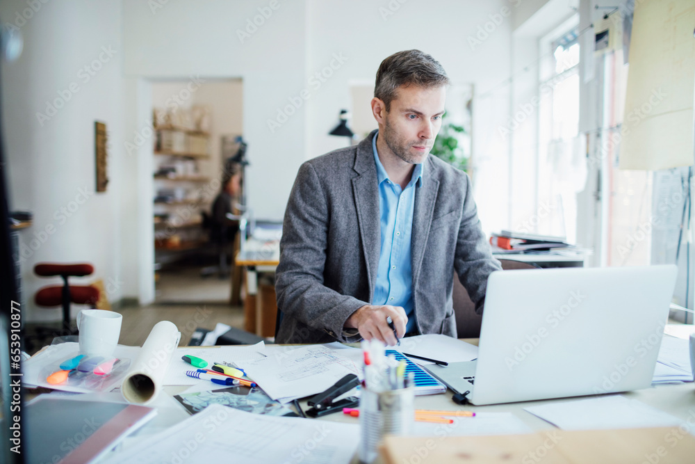 Middle aged Caucasian architect working on building plans in a modern company office Middle aged Caucasian architect working on building plans in a modern company office