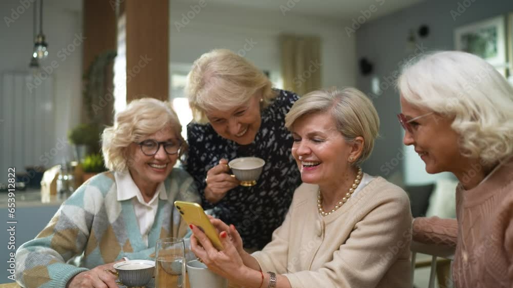 Senior group of female friends using the smartphone together at home Senior group of female friends using the smartphone together at home