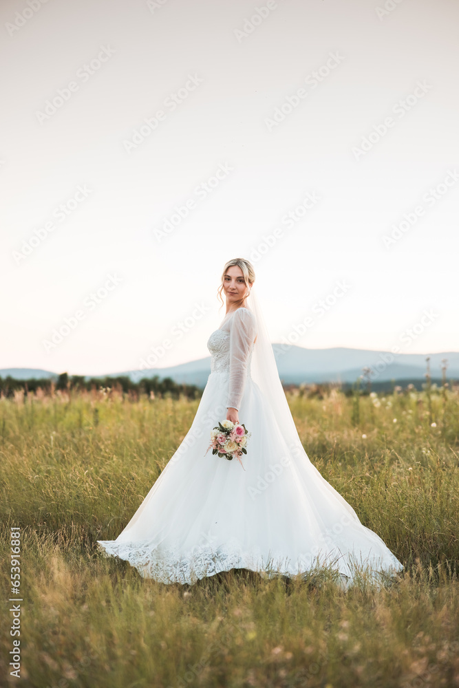 a shot of a beautiful bride in a white lace dress holding a bouquet of dried flowers in the middle of a field, a beautiful blonde, a happy bride in the middle of a wedding photo shoot, love, wedding 