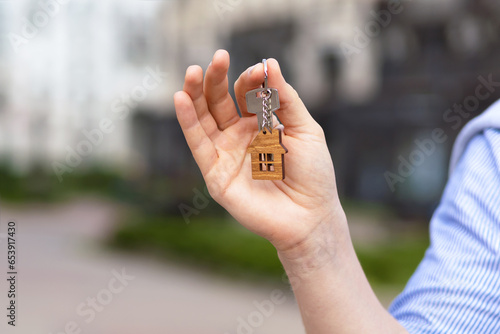 Man with key house keychain in hand. Realtor, landlord holding housekey. Buy, sale, rent real estate. mortgage, apartment renting, moving home, relocation, investment, flat tenancy, leasehold property