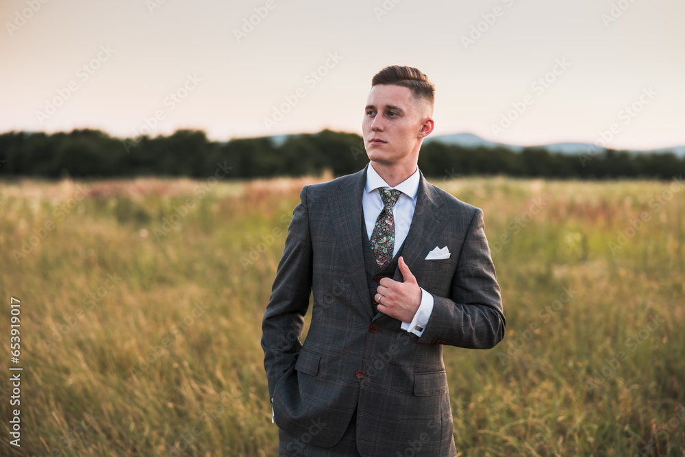 young man standing in a stylish suit young man standing in a stylish suit