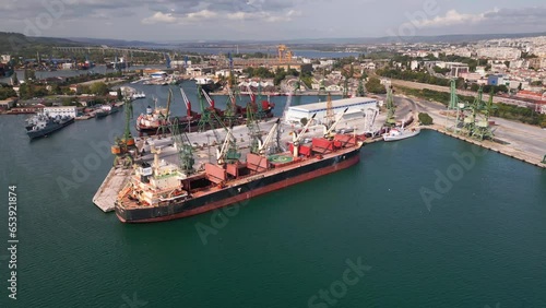 aerial view of a bustling seaport, where a massive cargo ship, a bulk carrier, is being loaded with wheat grains photo