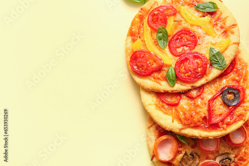 Different tasty mini pizzas on yellow background