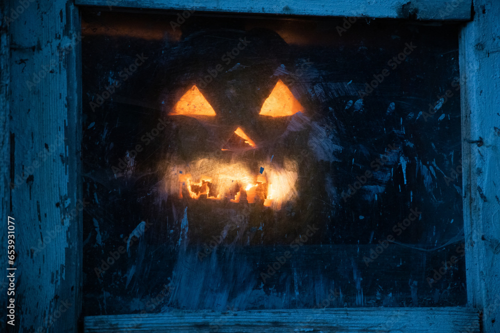 Fototapeta premium scary Halloween pumpkin glowing in window at night