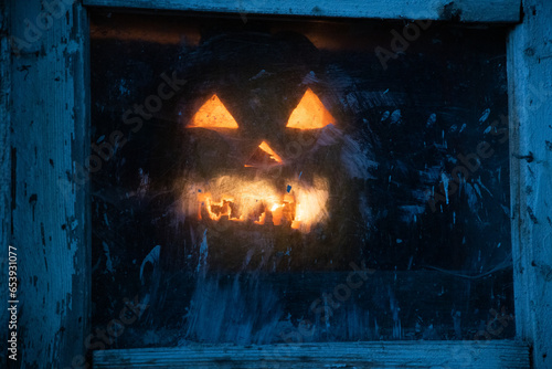 scary Halloween pumpkin glowing in window at night