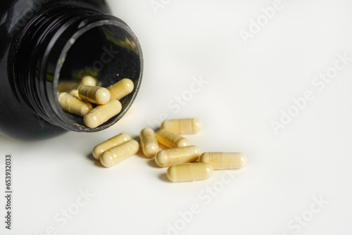 Vitamin D capsules on a green leaf with white background.