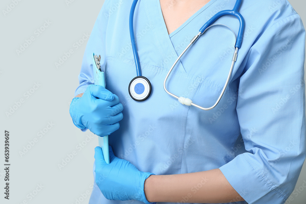 Female doctor with stethoscope and clipboard on grey background Female doctor with stethoscope and clipboard on grey background