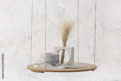 Gypsophila flowers, pampas grass and candle on hanging shelf near light wall in room