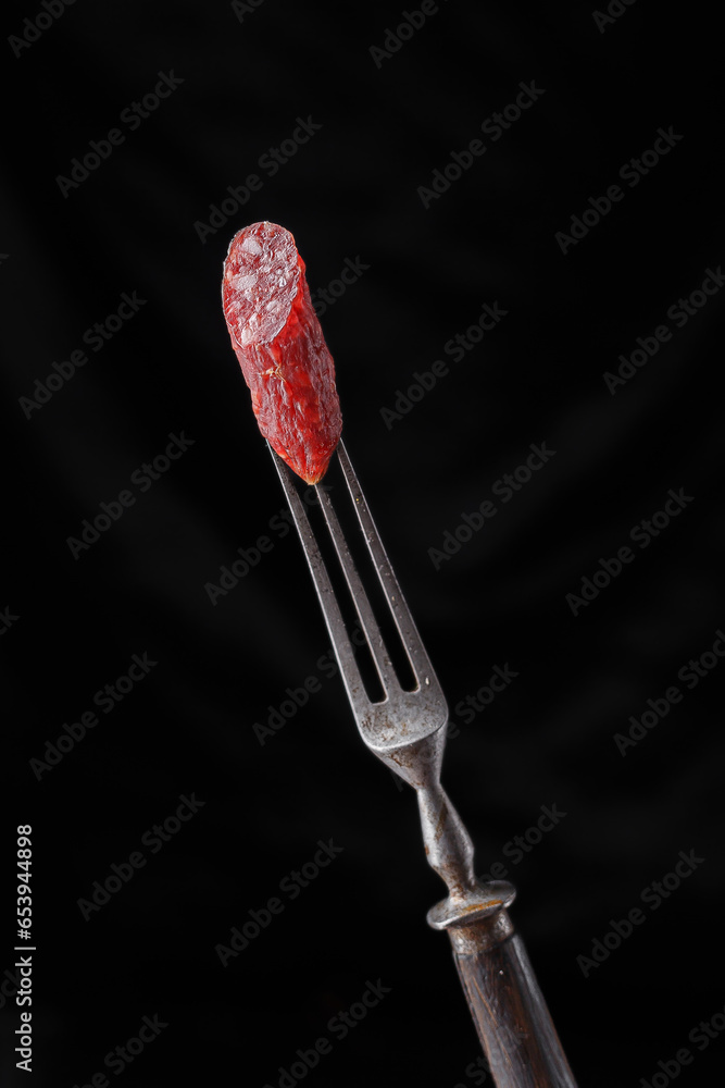 meat snacks on a fork, on a black isolated background meat snacks on a fork, on a black isolated background