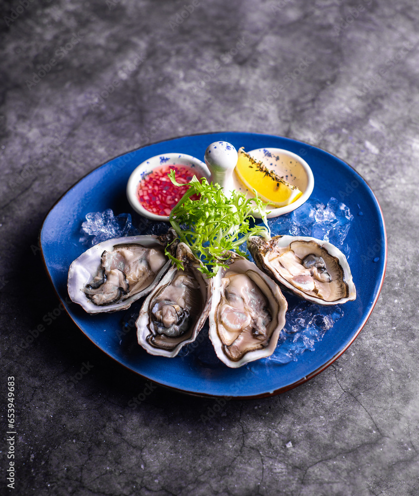 Oysters close-up. A dozen of raw oysters on a blue plate