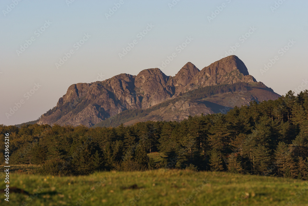 Basque landscape at golden hour during sunset with forest and mountain peak Erroilbide rock formation, Aiako Harria, Gipuzkoa, Basque Country, Spain