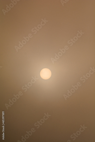 Bright sun obscured by dense fog and thick clouds.