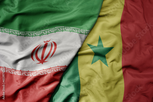 big waving realistic national colorful flag of iran and national flag of senegal .