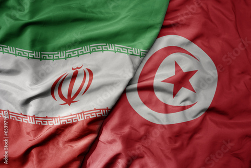 big waving realistic national colorful flag of iran and national flag of tunisia .