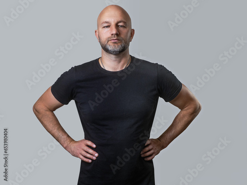 Bald man with beard in black t shirt on light color background. Man with athletic slim body. Sport and fitness concept. © mark_gusev