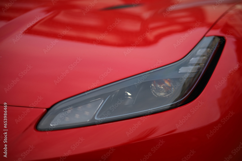 Close-up of the headlight of a red sports car.