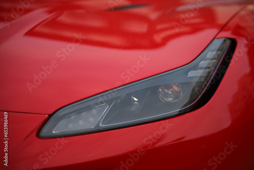 Close-up of the headlight of a red sports car. © Евгений Бордовский