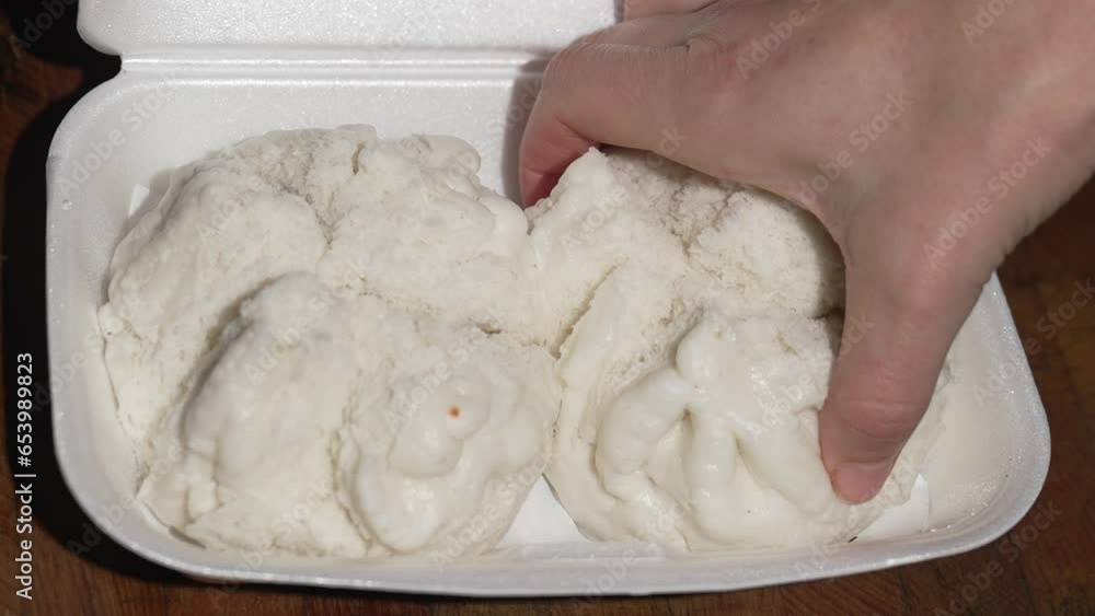 This video shows a hand feeling and selecting a steamed dim sum bun. This video shows a hand feeling and selecting a steamed dim sum bun.