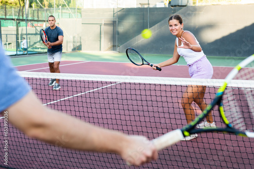 Focused young woman playing friendly tennis match on court. Concept of concentration in competition