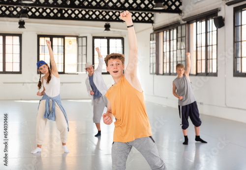 One young lady and few boys dancing modern dance on rehearsal