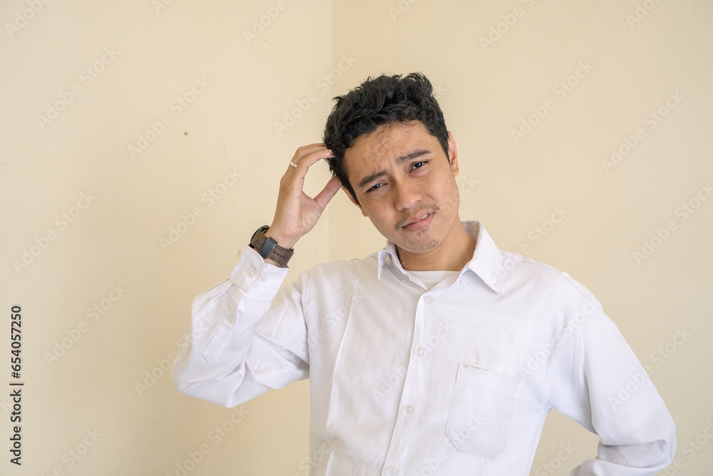 Indonesian office employee wear white clothes feel stress and unhappy expression. The photo is suitable to use for man expression advertising and fashion life style. Indonesian office employee wear white clothes feel stress and unhappy expression. The photo is suitable to use for man expression advertising and fashion life style.