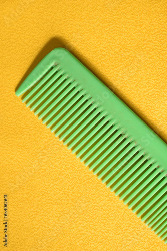 a green comb isolated on yellow background