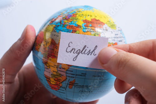 Hand holding notepaper with English wording on globe