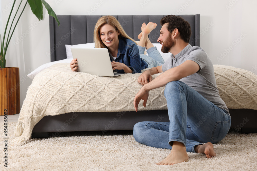 Happy couple spending time together and using laptop at home