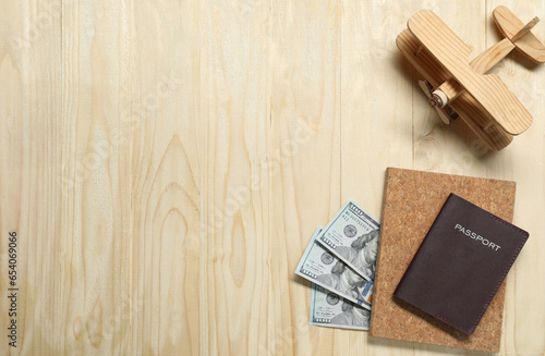 Flat lay composition with dollars, model of plane and passport on wooden table, space for text. Business trip © New Africa