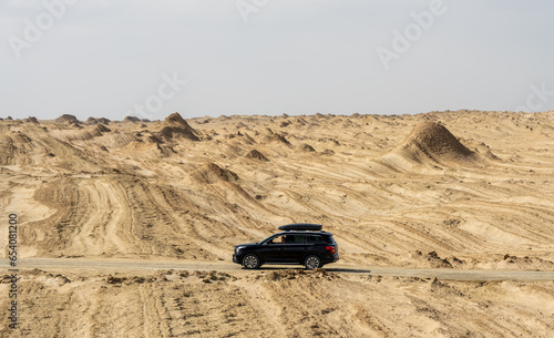A SUV vehicle drive on a road in Yardang landforms desert.
