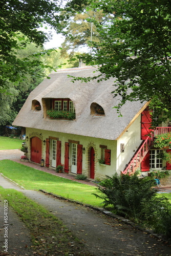 Maison normande aux volets rouges en toit de chaume