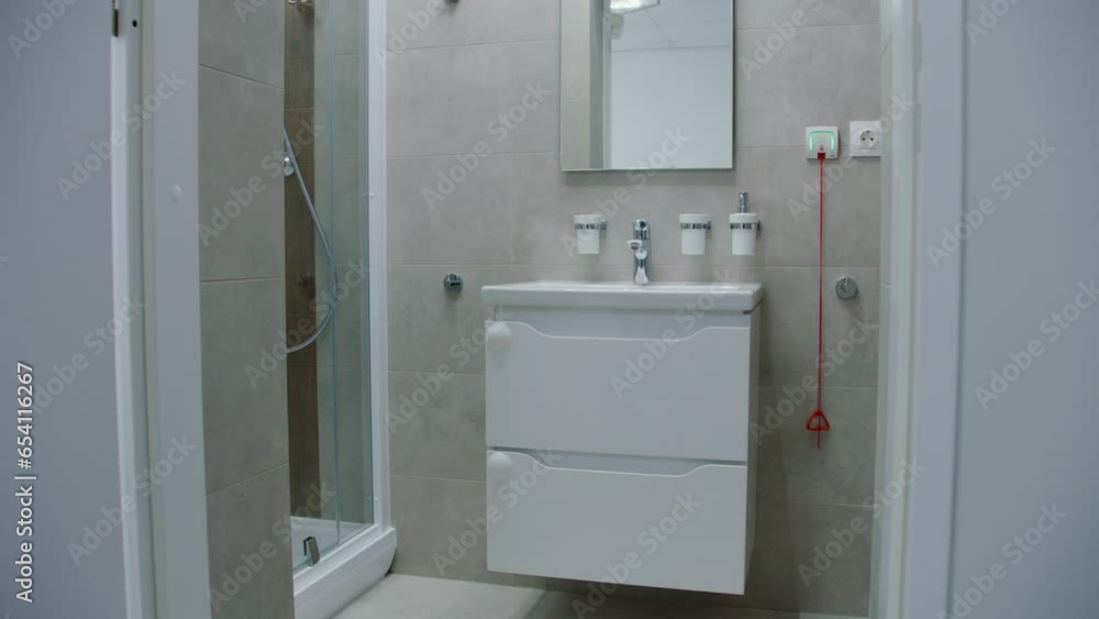 White sink with mirror above it in middle of bright and well-equipped bathroom with modern design in hospital ward. Sink, mirror, toilet and big comfortable shower in medical facility or clinic. White sink with mirror above it in middle of bright and well-equipped bathroom with modern design in hospital ward. Sink, mirror, toilet and big comfortable shower in medical facility or clinic.