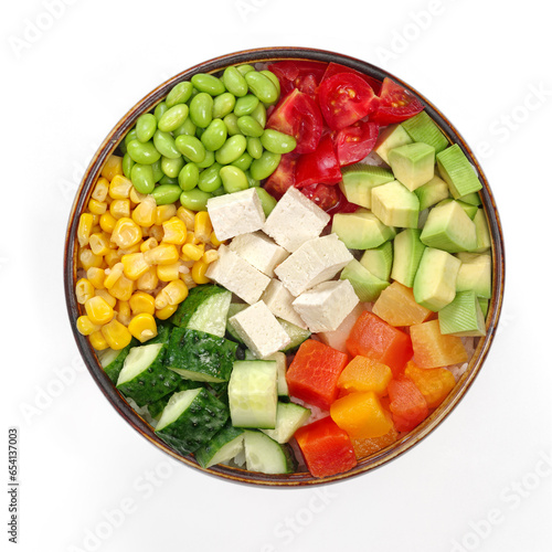 Top view of bowl of fresh beans and vegetables with tofu and sauce poke on white background