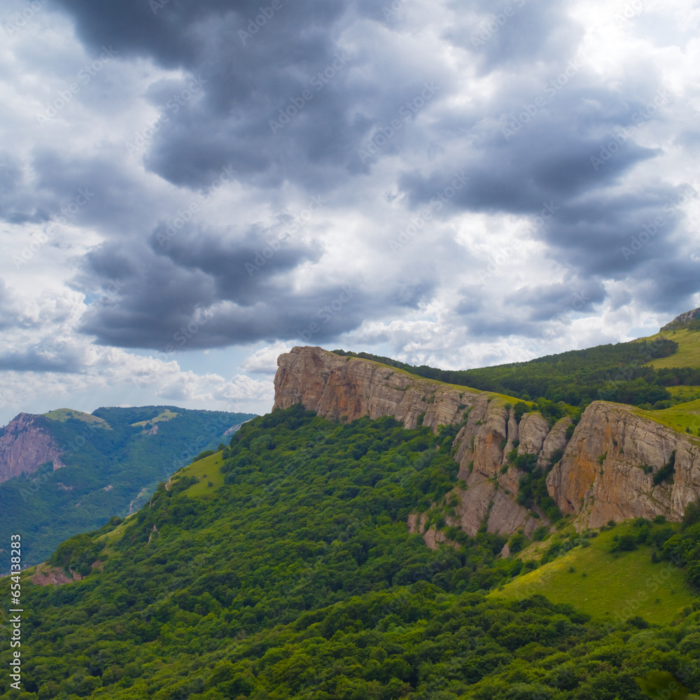 mountain cliff on dense cloudy sky background