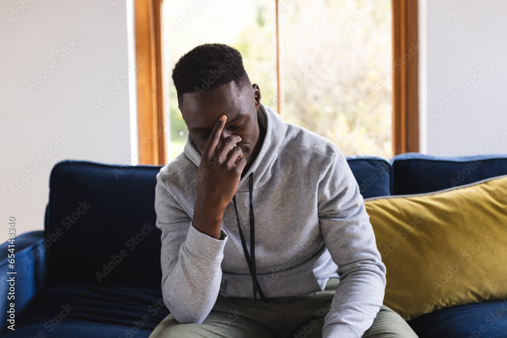 Sad african american man sitting on sofa having video call at home Sad african american man sitting on sofa having video call at home