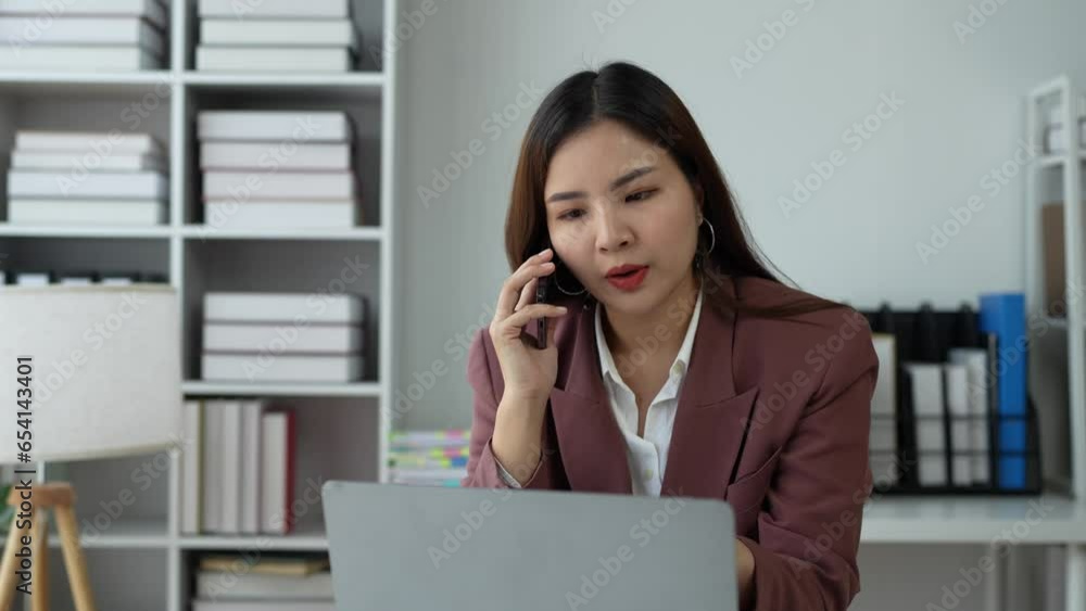 Attractive Asian businesswoman Use your laptop to watch your computer and talk on the phon. Consult customers, sit at a table. financial officer making a mobile business call Discuss work with clients Attractive Asian businesswoman Use your laptop to watch your computer and talk on the phon. Consult customers, sit at a table. financial officer making a mobile business call Discuss work with clients