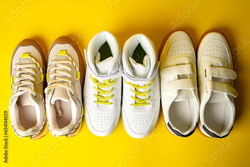 Several pairs of fashion trendy sport shoes on yellow background