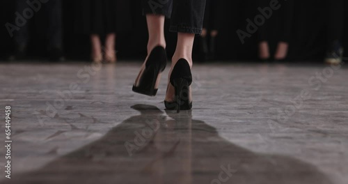 Follow cam shot of stepfoot of girl heels on defile catwalk. Legs attractive woman in model show fashion on catwalk closeup. Models walk on podium. Slender legs on thin high black stilettos photo